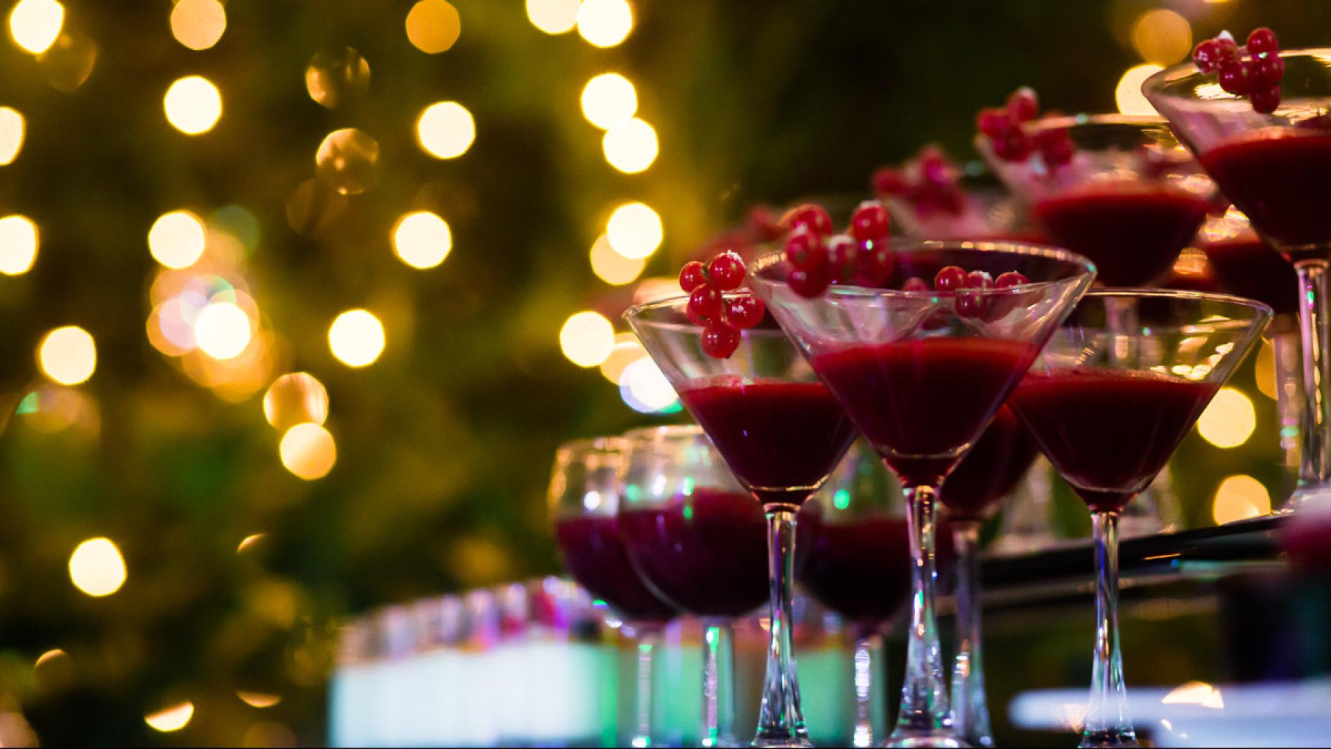 Cocktail rossi in bicchieri da Martini con decorazioni di frutti rossi, luci sfocate sullo sfondo.