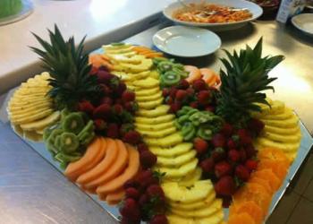 Un vassoio di frutta fresca con ananas, fragole, kiwi, melone e arance.